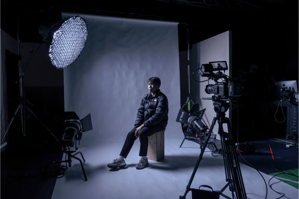 Man sits on stool to demonstrate film set up for music video