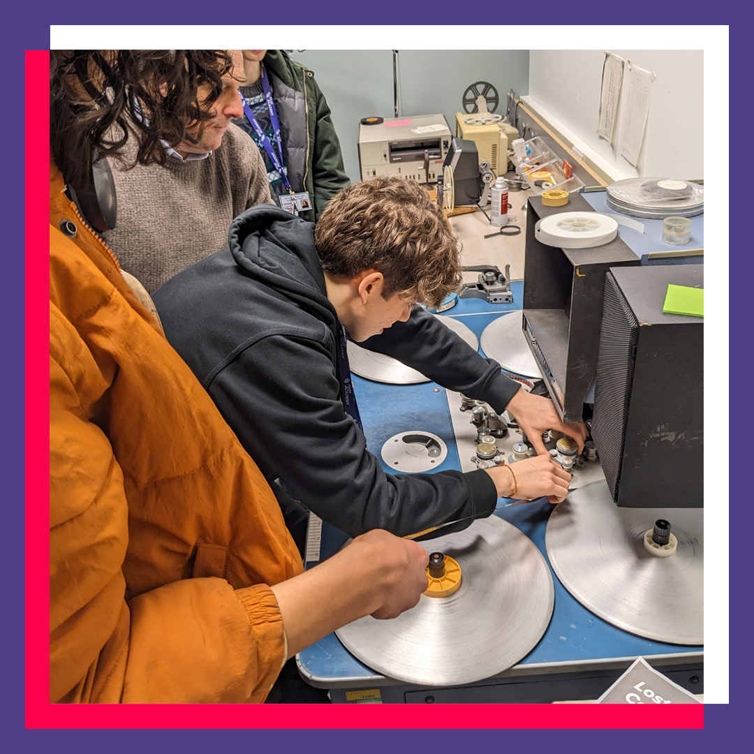 Young person fiddles with old film in a machine,