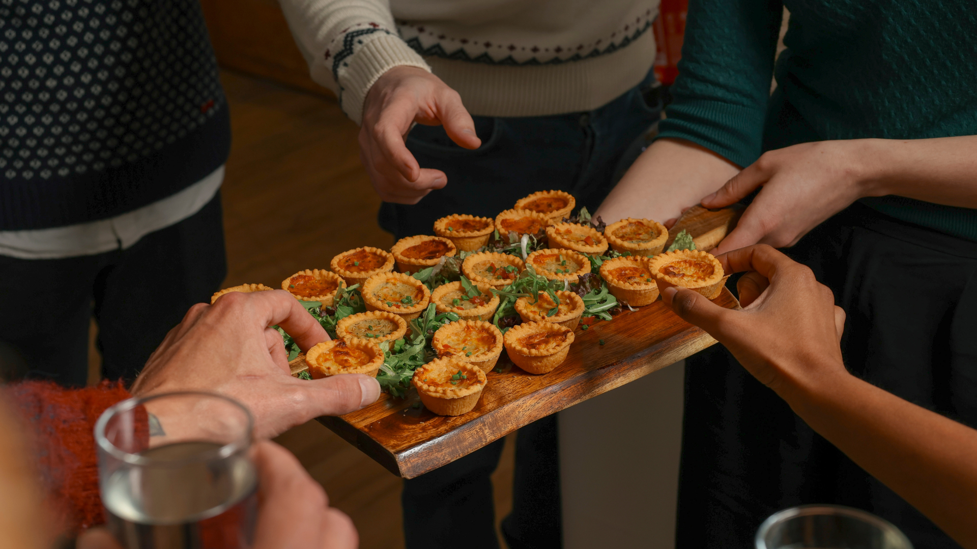 Hands reach out to grab Christmas bites off a wooden board
