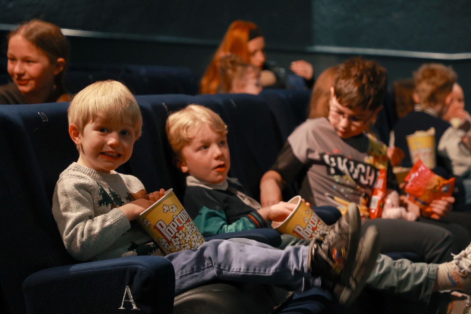 Happy children in the cinema eating popcorn